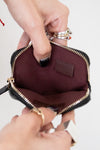 Close-up of a hand holding an open maroon pouch with gold zipper.
