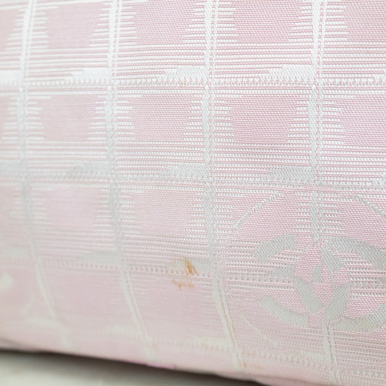 Close-up of a pink textured fabric with a subtle pattern on a light wooden surface.