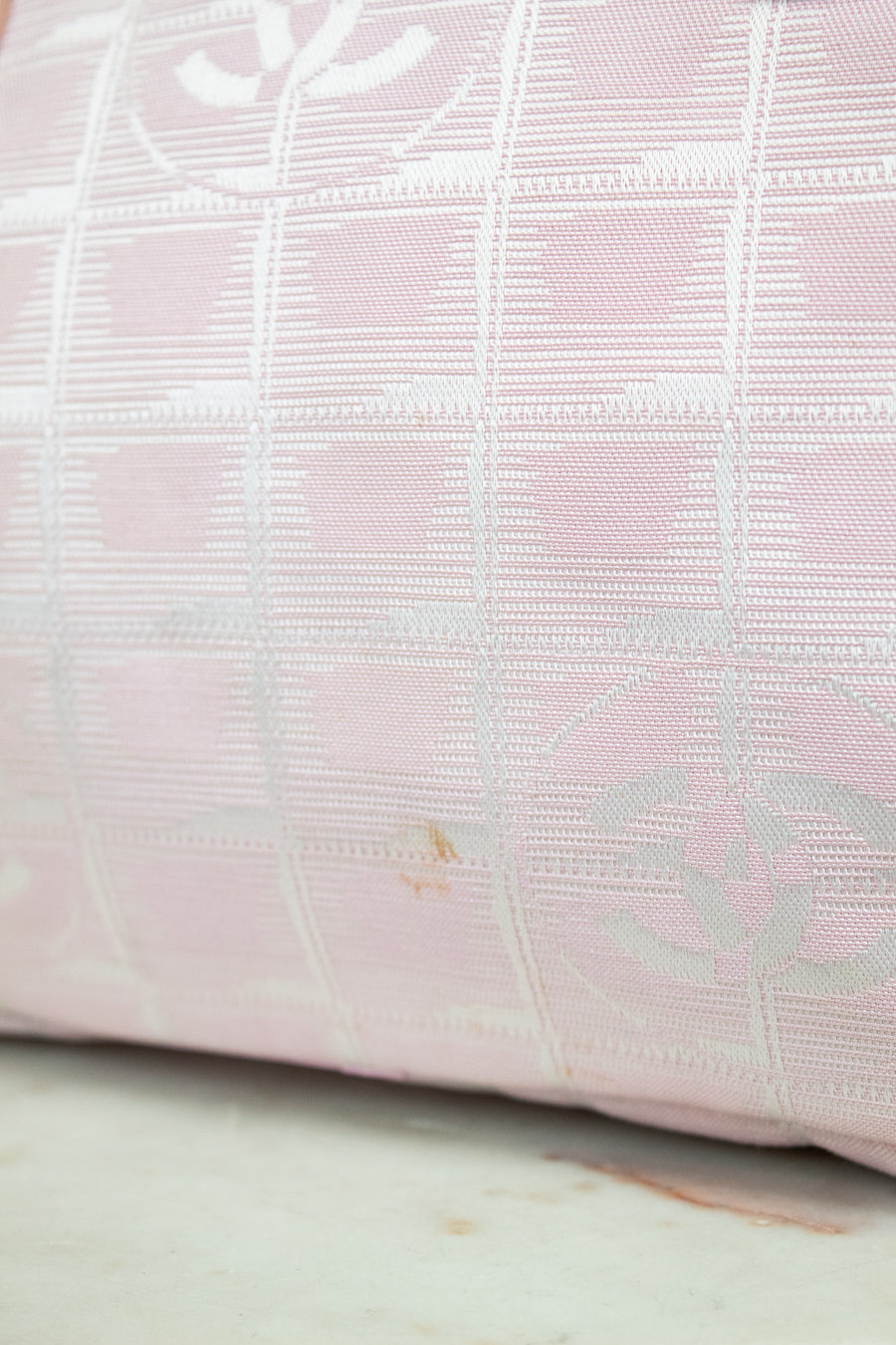 Close-up of a pink textured fabric with a subtle pattern on a light wooden surface.