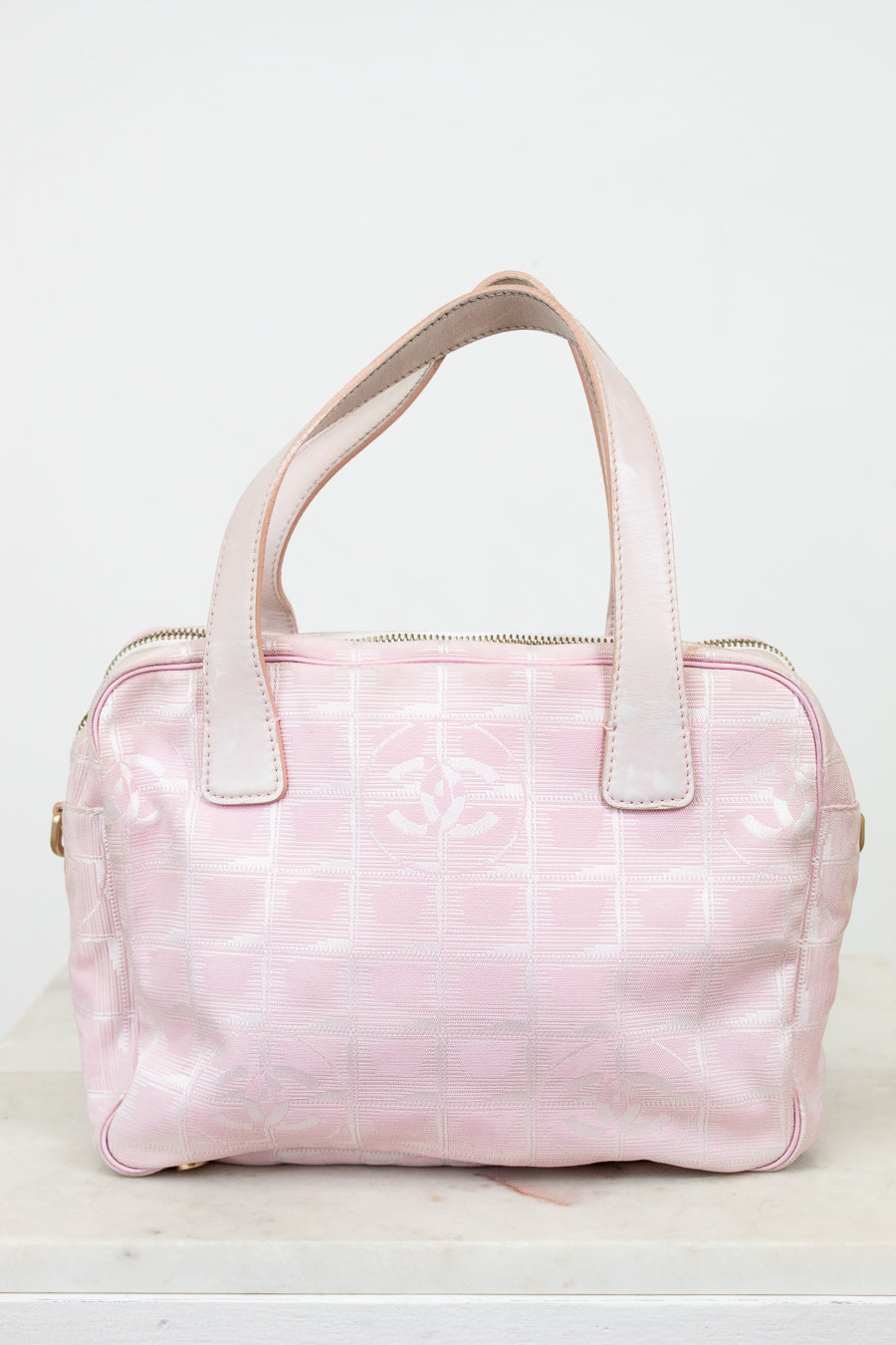 Pink handbag with white handles on a light gray background