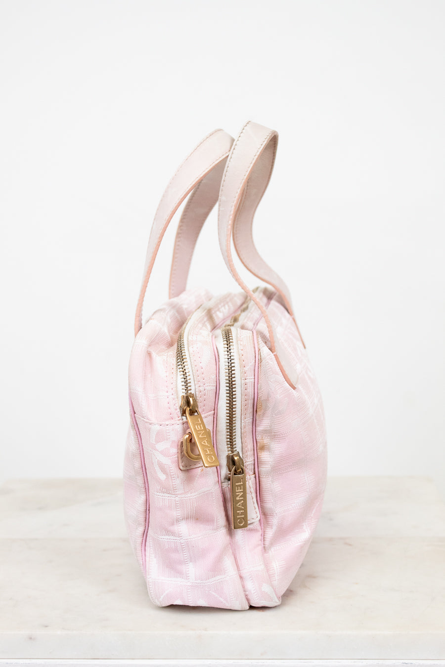 Pink drawstring bag with gold zipper on a white background