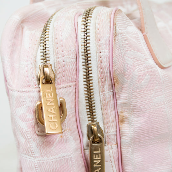 Close-up of a pink Chanel handbag with gold zippers on a light background