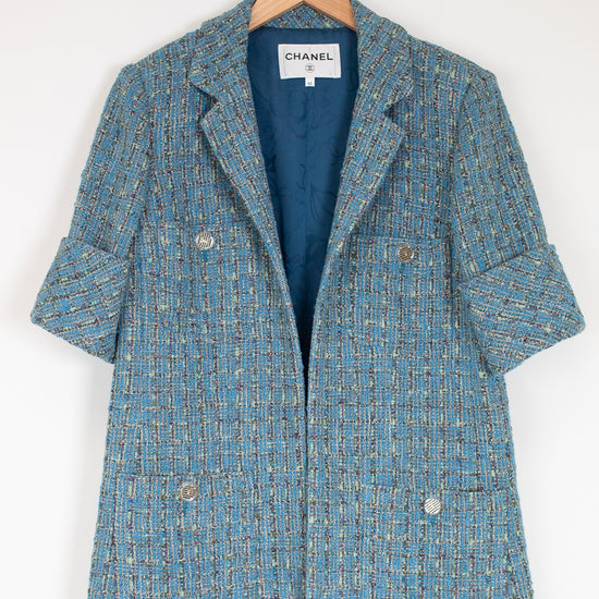 Blue tweed coat on a hanger with Chanel label