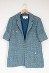 Blue tweed coat on a hanger with Chanel label