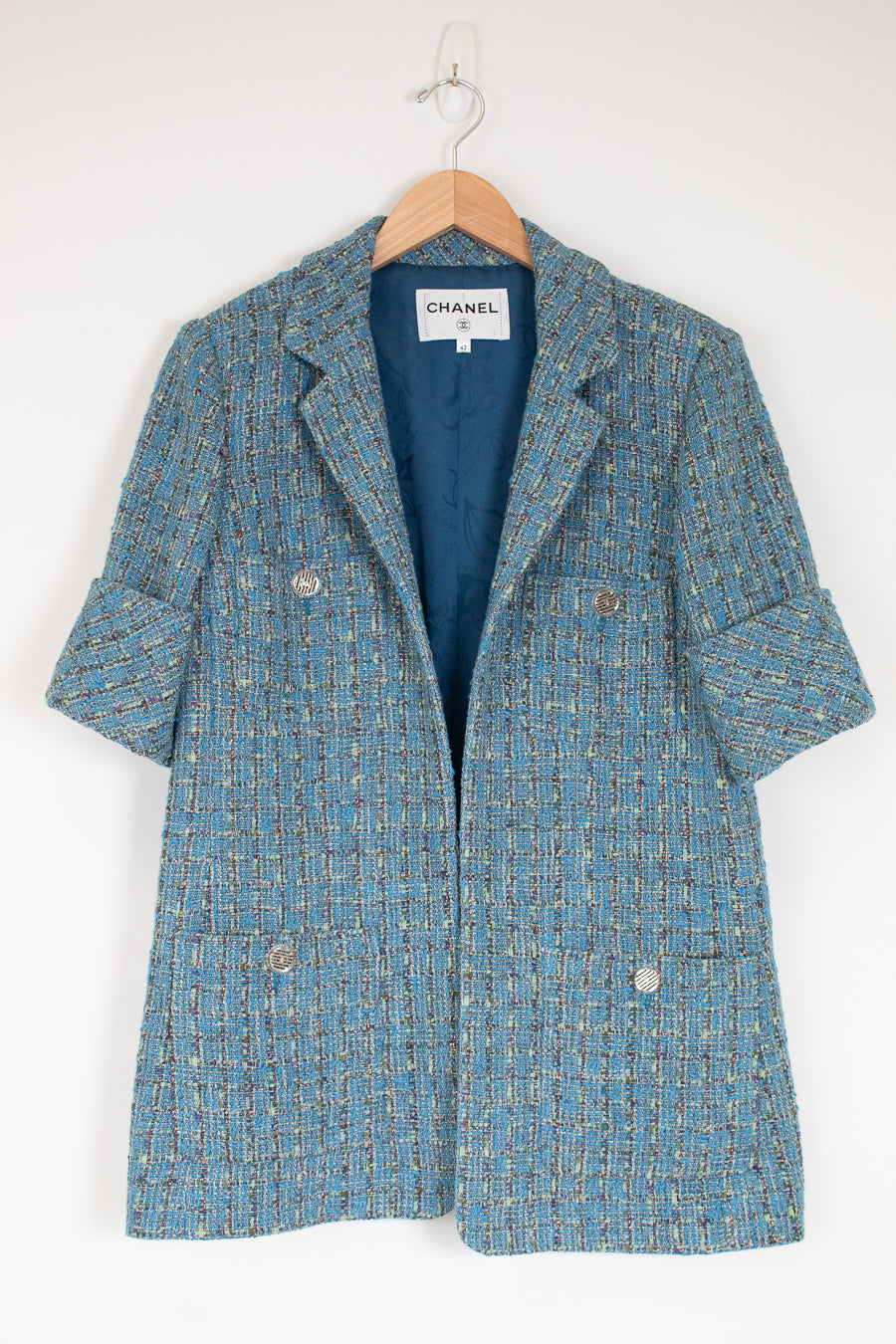 Blue tweed coat on a hanger with Chanel label