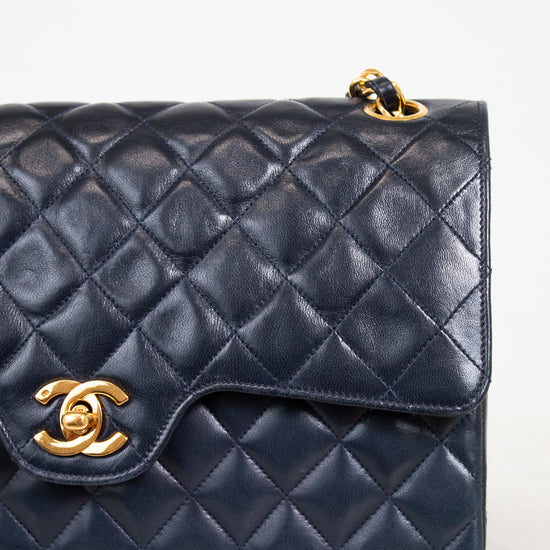 Navy blue quilted handbag with gold hardware on a light background