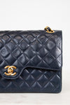 Navy blue quilted handbag with gold hardware on a light background