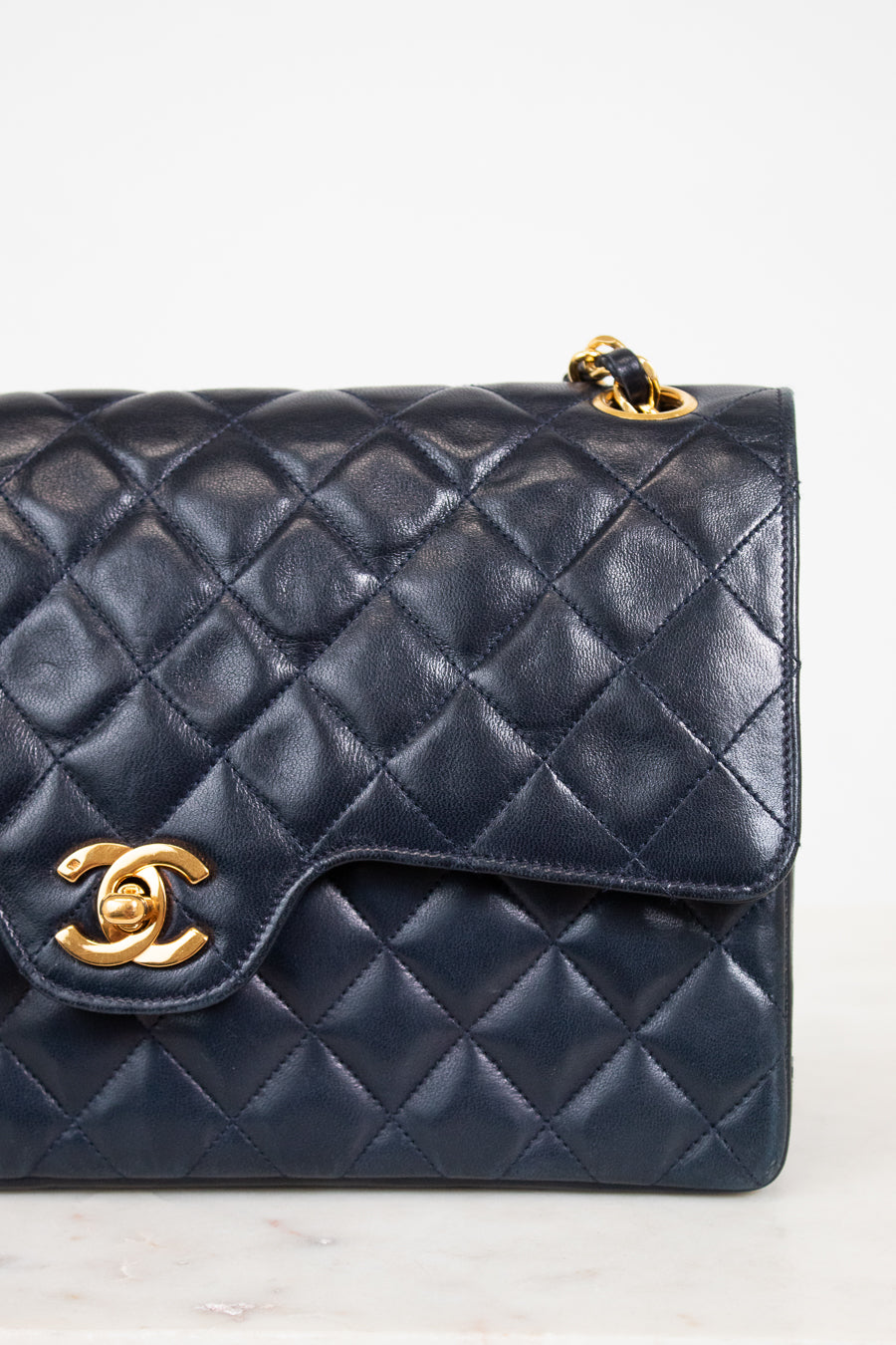Navy blue quilted handbag with gold hardware on a light background