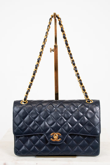 Navy blue quilted handbag with gold chain strap on a white background