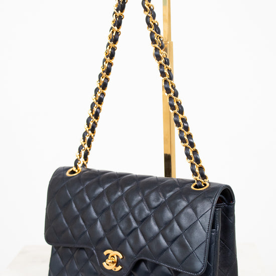 Navy quilted handbag with gold chain strap on a white background