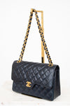 Navy quilted handbag with gold chain strap on a white background