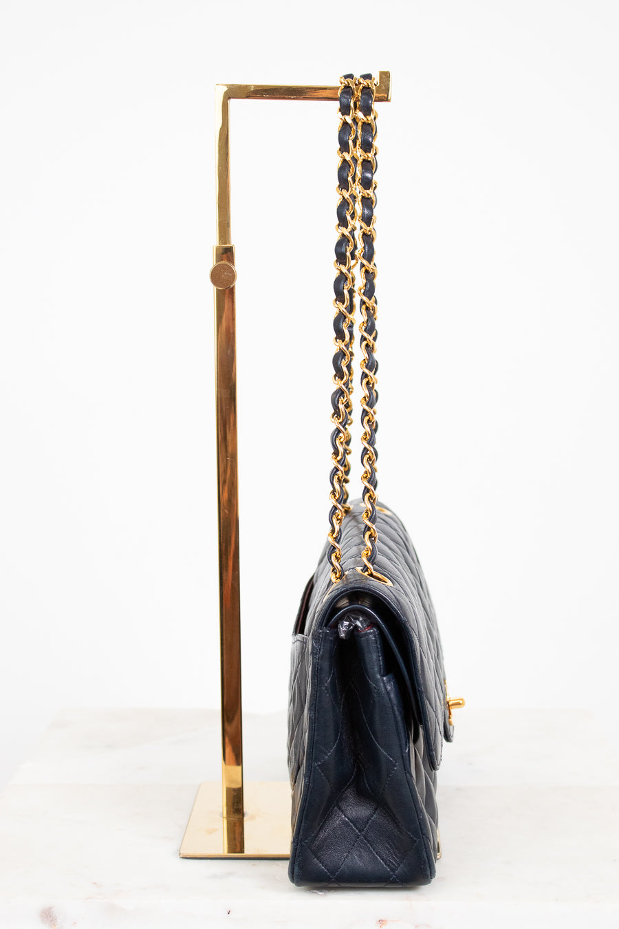 Navy handbag with gold chain strap on a white background