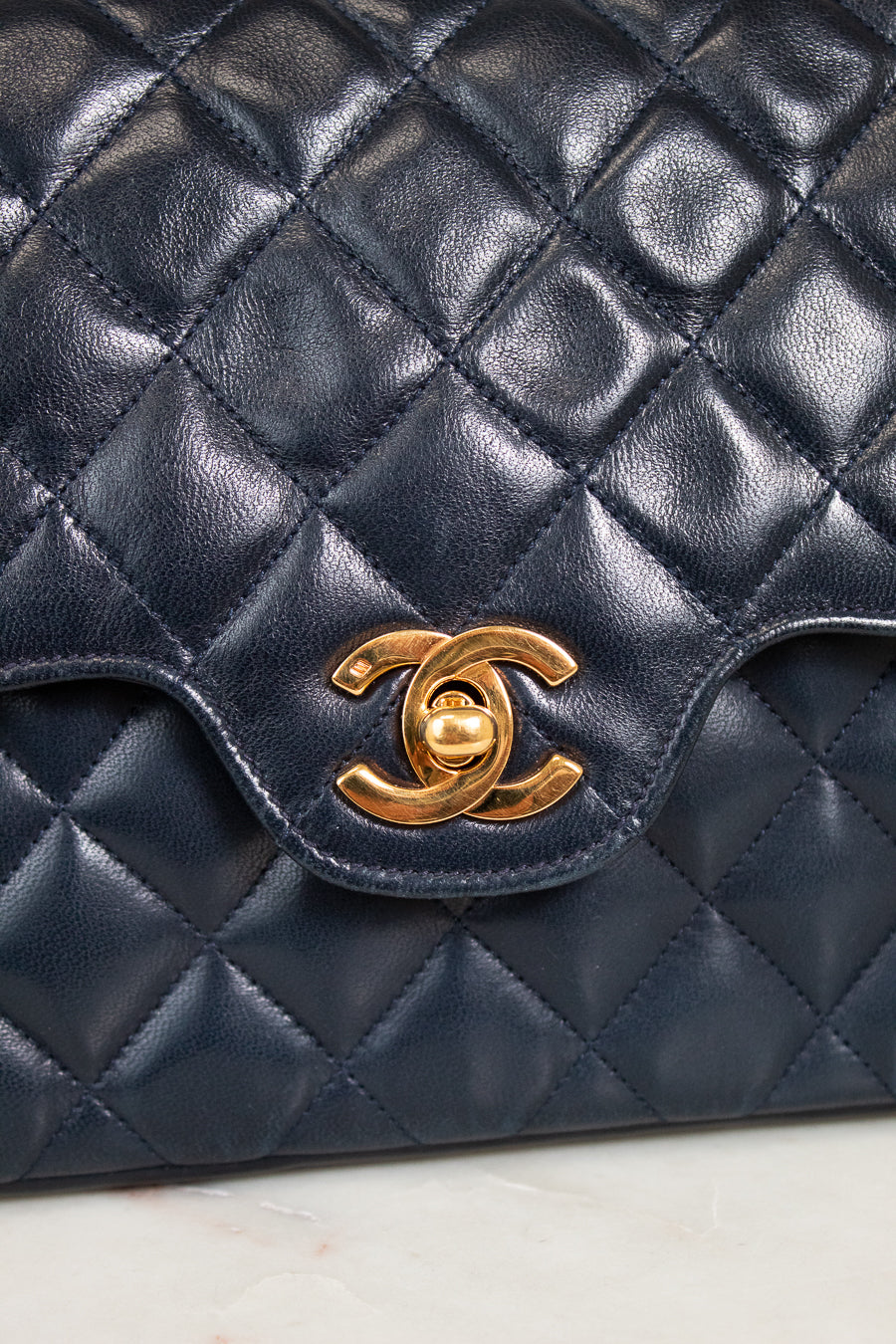 Navy quilted leather handbag with gold Chanel logo on a light background