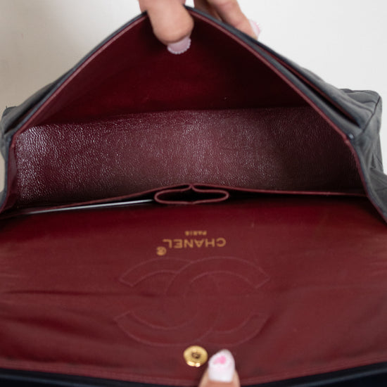 Interior of Chanel flap bag with maroon lining on a white background 