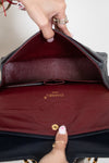 Interior of Chanel flap bag with maroon lining on a white background 