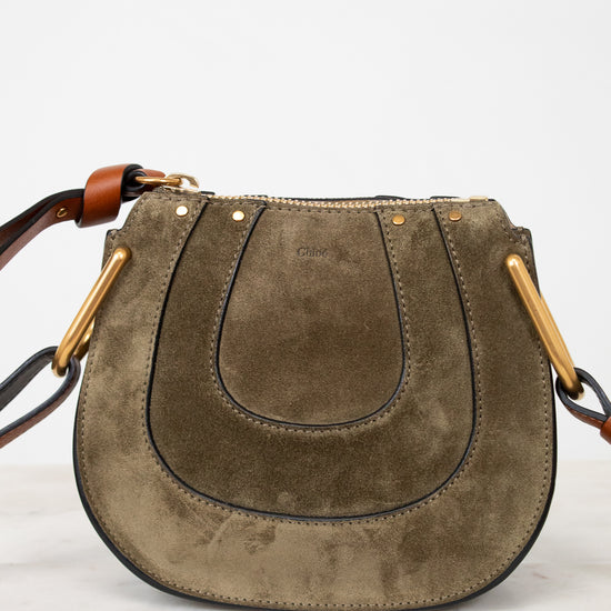 Olive suede handbag with gold accents on a white background