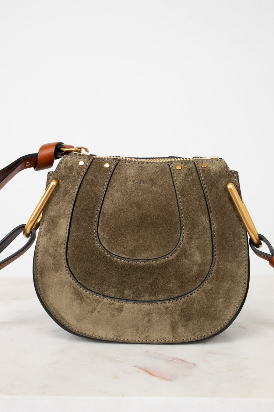 Olive suede handbag with gold accents on a white background