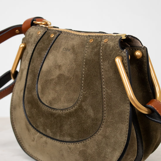 Olive suede handbag with gold hardware on a white background
