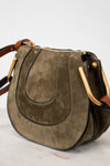 Olive suede handbag with gold hardware on a white background