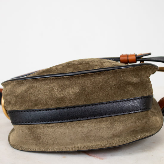 Olive suede bag with black strap on a white background