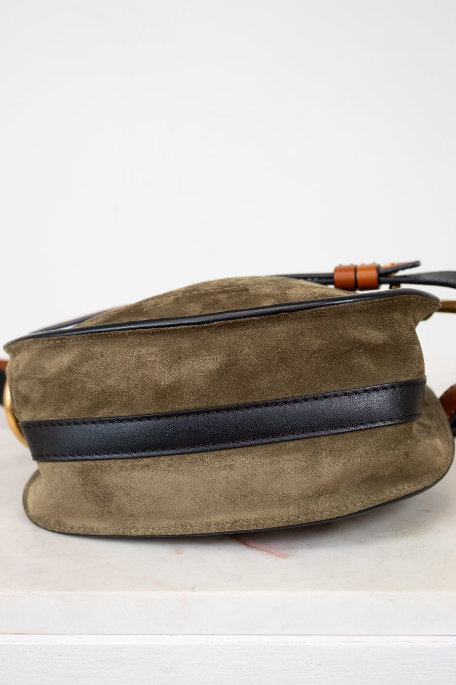 Olive suede bag with black strap on a white background