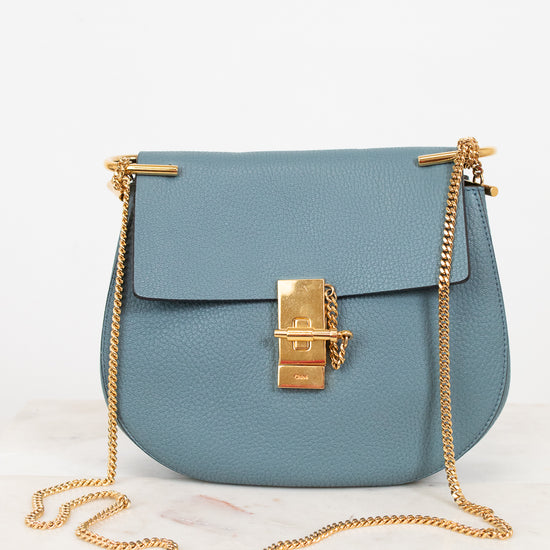 Blue handbag with gold chain detail on a white background