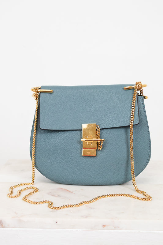 Blue handbag with gold chain detail on a white background
