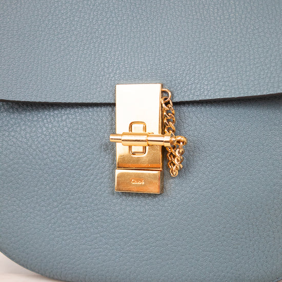 Blue handbag with a gold clasp on a light background