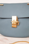 Blue handbag with a gold clasp on a light background
