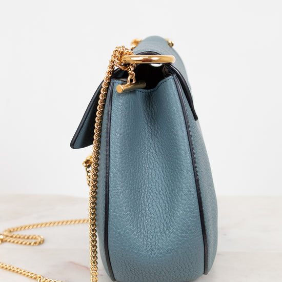 Blue handbag with a gold chain on a white background