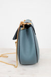 Blue handbag with a gold chain on a white background