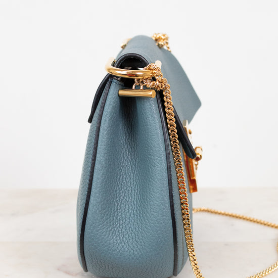 Blue handbag with a gold chain on a white background