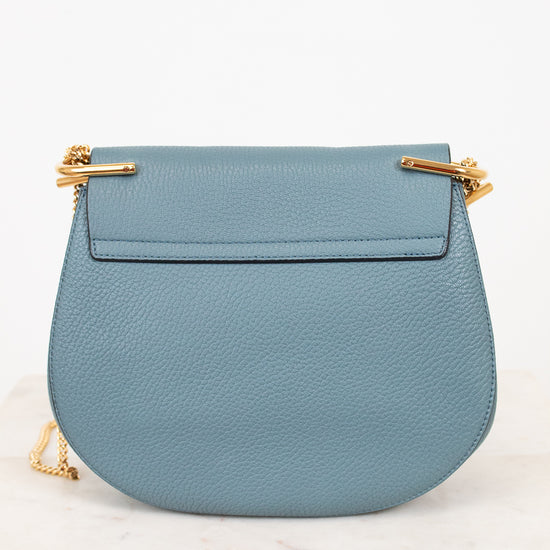 Blue handbag with gold accents on a white background