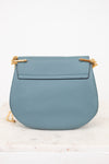 Blue handbag with gold accents on a white background