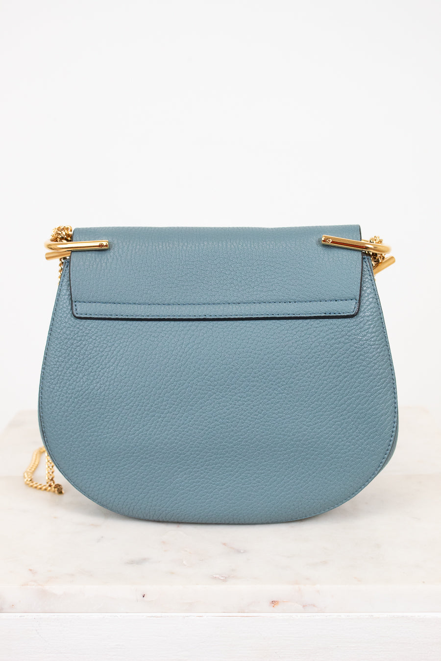 Blue handbag with gold accents on a white background