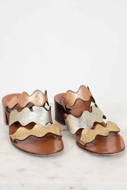 Pair of sandals with wavy metallic design on a white background