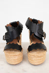 Black wedge sandals with wicker soles on a white background