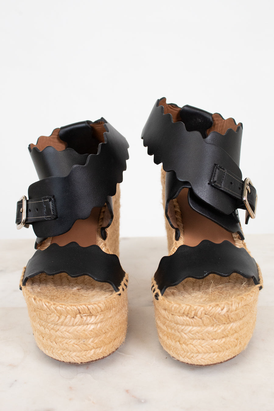 Black wedge sandals with wicker soles on a white background
