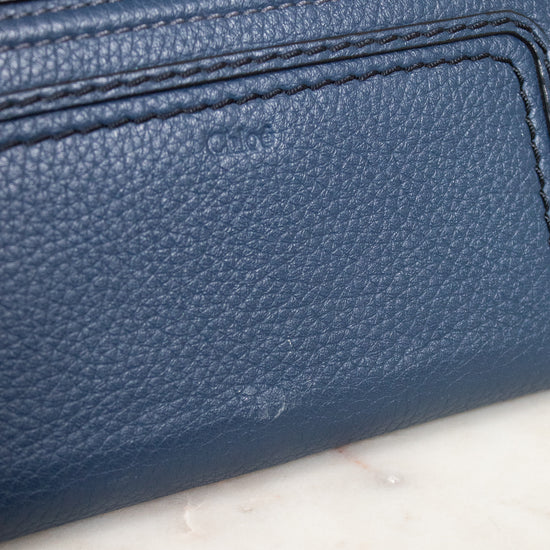 Close-up of a blue textured wallet with gold accents on a marble surface
