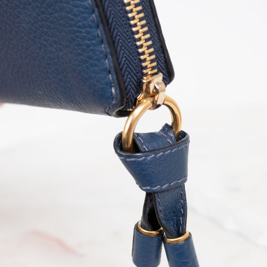 Blue leather wallet with gold zipper and matching strap on a white background