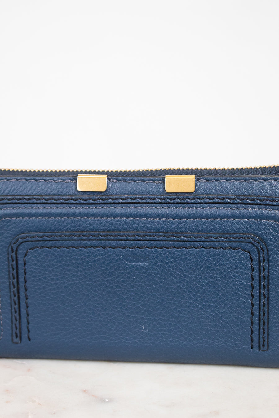 Blue wallet with gold zipper on a light gray background