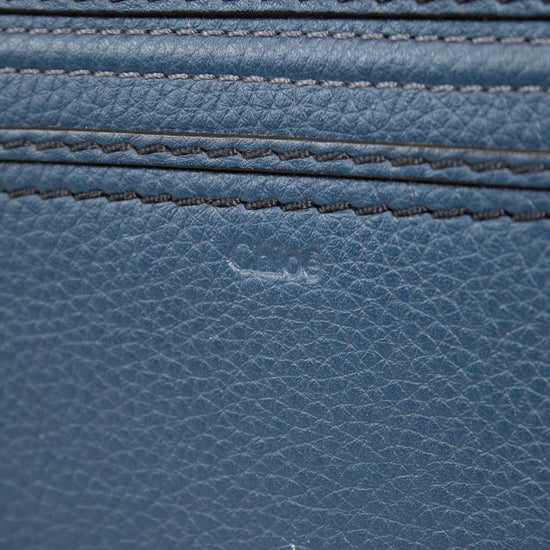 Close-up of a blue leather wallet with gold zipper pulls.