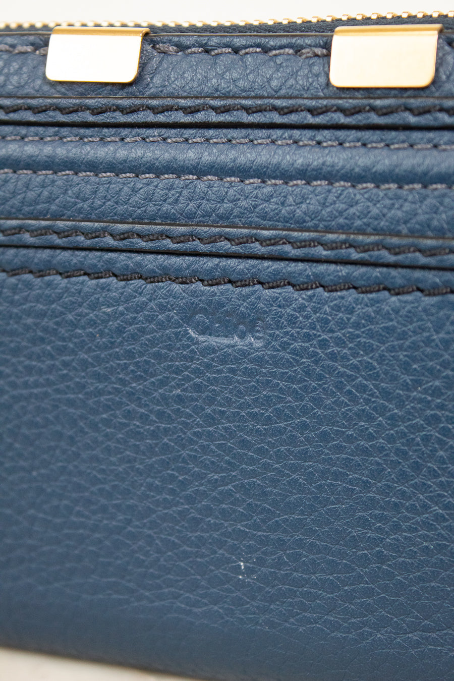 Close-up of a blue leather wallet with gold zipper pulls.