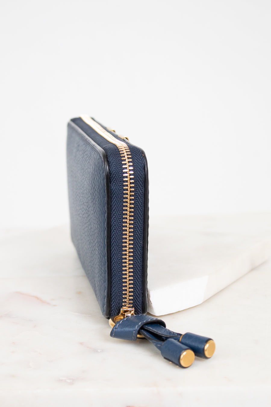 Navy blue wallet with gold zipper on a white background