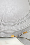 Close up of grey leather saddle crossbody bag with hold hardware on white background