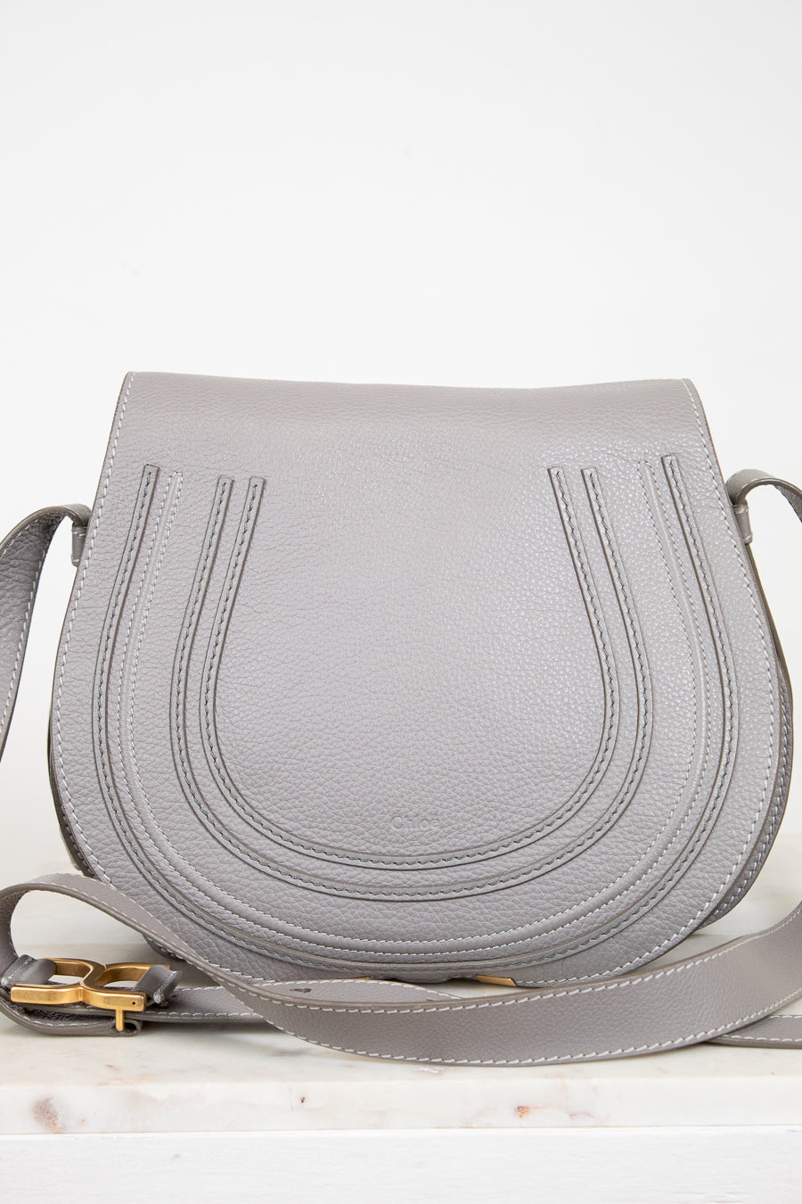 Grey leather saddle crossbody bag on white background