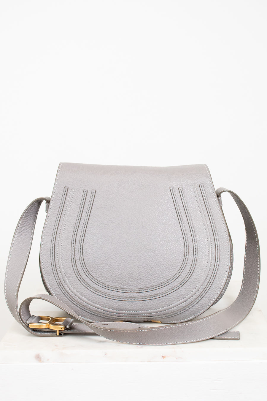 Grey leather saddle crossbody bag on white background