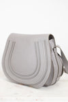 Grey leather saddle crossbody bag on white background