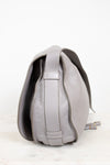 Side view of grey leather saddle crossbody bag on white background