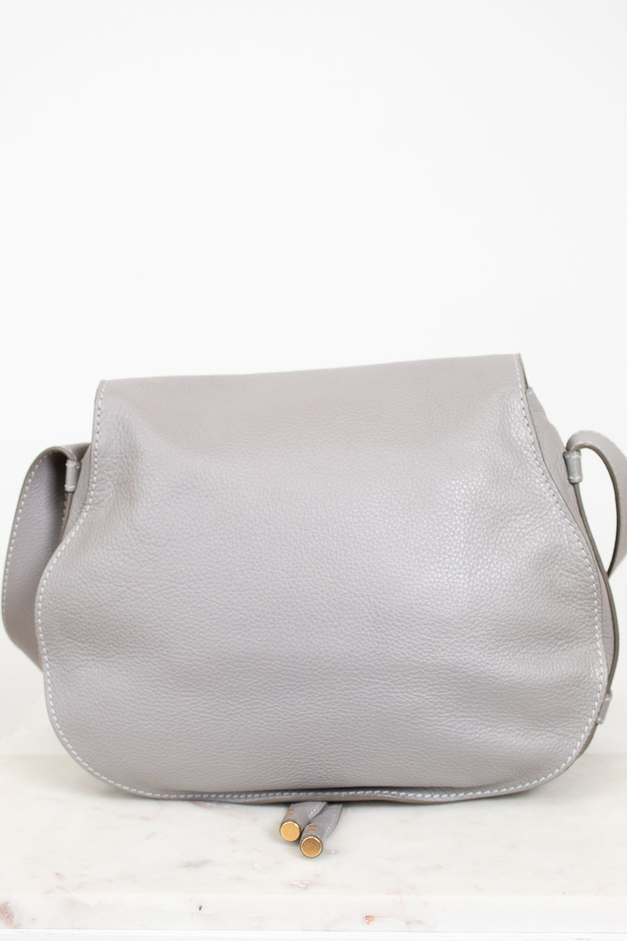 Back view of grey leather saddle crossbody bag on white background